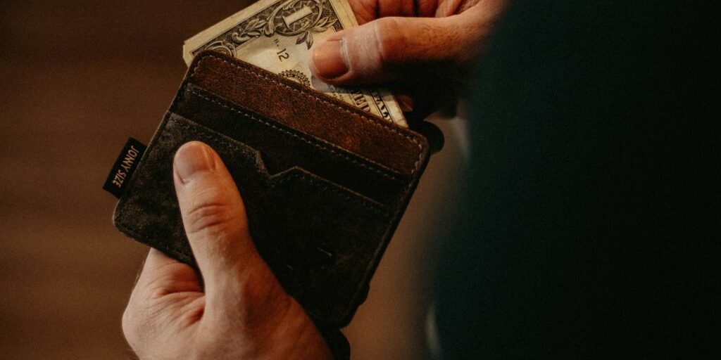 person getting 1 U.S. dollar banknote in wallet